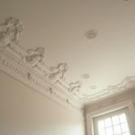 Intérieur haussmannien avec moulures de plafond élégantes et rosaces décoratives.